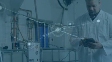 Bir erkek işçi bir fabrikada dijital tablet kullanıyor. Dijital bir şehirde bir bağlantı ağı görülüyor. Bu video küresel bağlantılar, hesaplama ve dijital arayüzler hakkında.