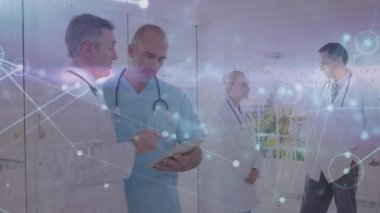 Dijital tablet üzerinde tartışan çok ırklı doktorların çizgileriyle bağlantılı noktaların animasyonu. Dijital bileşik, çoklu pozlama, takım çalışması, tıbbi, sağlık ve teknoloji konsepti.