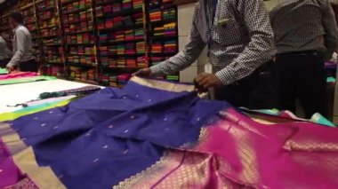 Chennai, Hindistan - 17 Ekim 2021: Erkekler Kumaş Satıcısı, Diwali festivali sırasında bir tekstil dükkanındaki müşterilere Saree 'yi gösteriyor ve aile en son geleneksel Hint kıyafetlerini almaktan keyif alıyor.