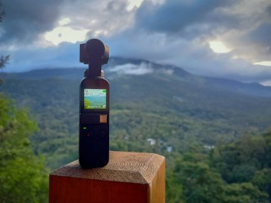 Munnar, Hindistan - 16 Nisan 2022: DJI Osmo Pocket kamera geçen bulutların hızlandırılmış videosunu çekiyor - hareket kamerası tripod olmadan çalışıyor.