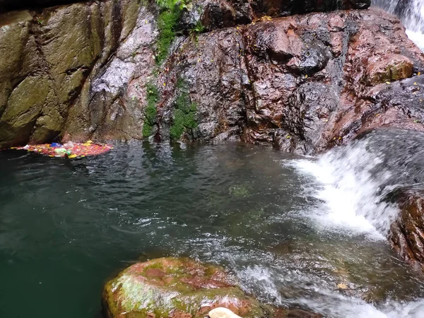 Water and nature pollution - bunch of waste dumped on water falls.