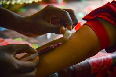 Closeup view of doctor's hands taking a blood sample from pregnant lady. swab is pressed onto the injection site during the blood collection.