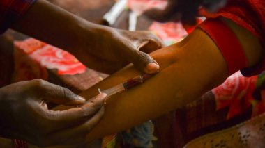 Closeup view of doctor's hands taking a blood sample from pregnant lady. swab is pressed onto the injection site during the blood collection.