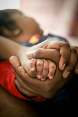 Parenthood Concept - Happy Mom and Dad are holding Baby Finger on hands. Parents are holding the hand and finger of a newborn baby