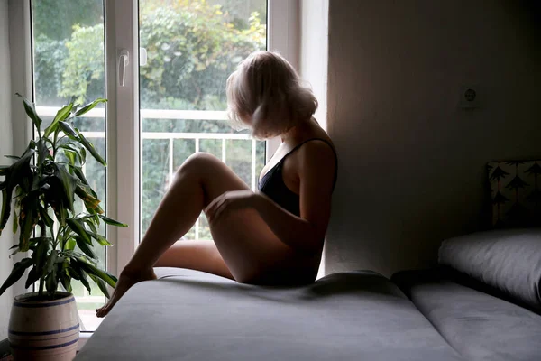 Güzel ve genç birbayan oturan ve evde penceresine bakarak iç çamaşırı