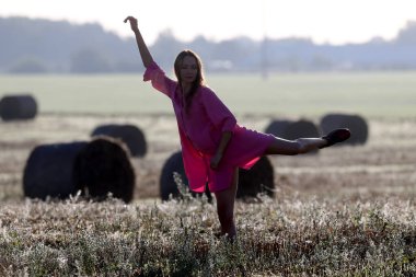 Güzel bir kız pembe iç çamaşırlarıyla tarlalarda dans ediyor.