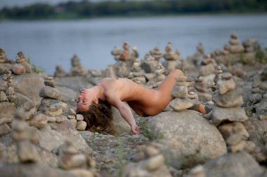 Genç ve güzel bir kadın sahilde yaz tatilinin tadını çıkarıyor. Taş üstünde seksi bir model