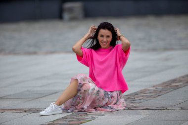 Genç bir kız taş kaldırımda oturuyor.