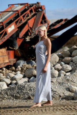 Metal bir yapının arkasında poz veren güzel sarışın kız modeli.