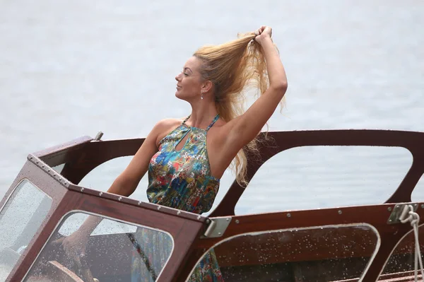 Blond caucasian woman driving a sport motor boat on a lake at summer