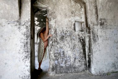 A flexible young woman performing a vertical split in an abandoned fort