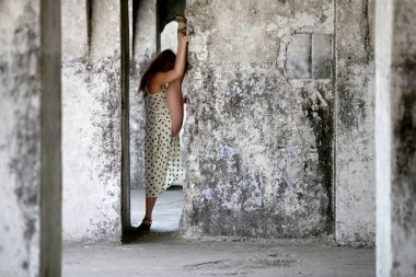 A flexible young woman performing a vertical split in an abandoned fort