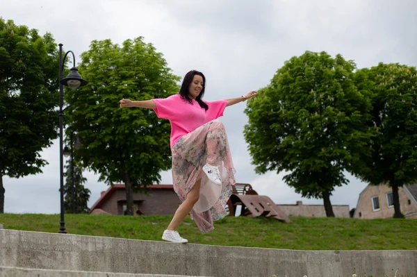 Χαρούμενο Μελαχρινό Κορίτσι Φωτεινά Ρούχα Πηδάει Στο Ανάχωμα Του Ποταμού — Φωτογραφία Αρχείου