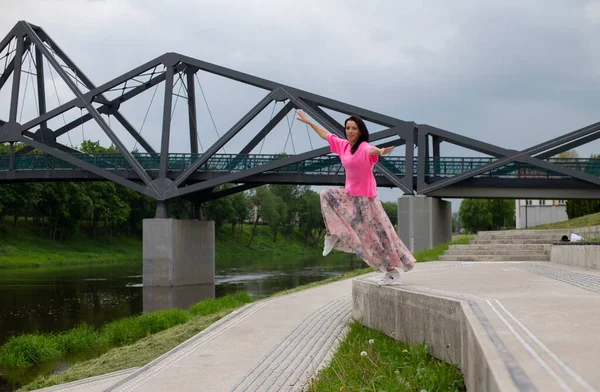 Parlak Elbiseli Neşeli Siyah Saçlı Kız Nehir Kenarında Atlıyor — Stok fotoğraf