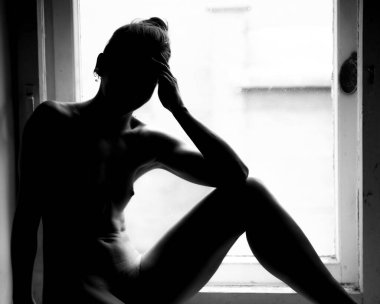 Camda poz veren şık bir kadının silueti..