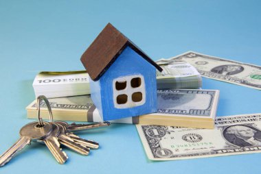 Bir ev modeli, içinde avro ve dolar banknotları olan desteler, bir sürü anahtar, bir konsept, çerçevenin ortasına odaklan