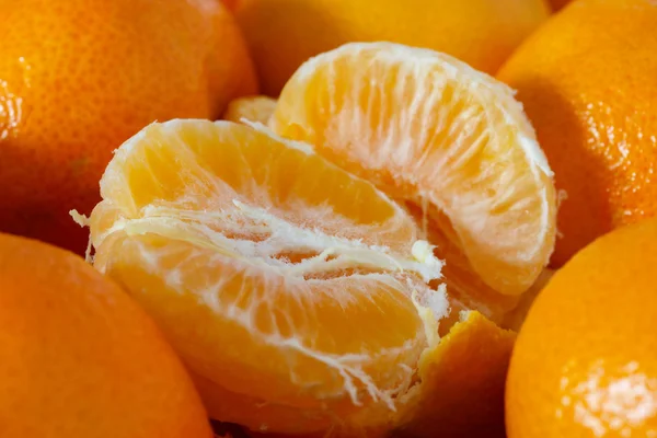 Half peeled tangerine surrounded by unpeeled tangerines — Stock Photo, Image