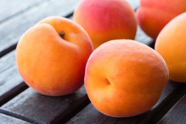 Koyu ahşap masa üzerinde düzenlenmiş Bbeautiful olgun kayısı.