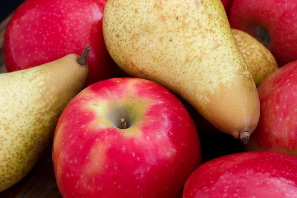 Manzanas rojas mixtas y peras dispuestas en madera oscura . — Foto de Stock