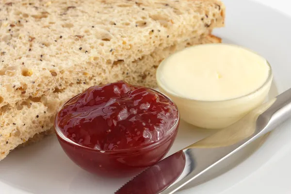 Dos rebanadas de pan multigrano con mermelada y mantequilla en platos —  Fotos de Stock