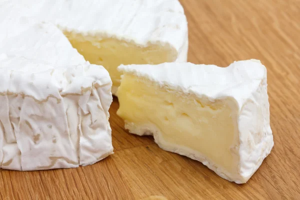 Tranche de fromage blanc découpée dans un grand rond sur une surface de bois . — Photo