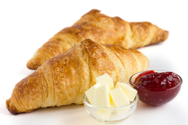 Dos croissants sobre una superficie blanca con mantequilla y mermelada . — Foto de Stock