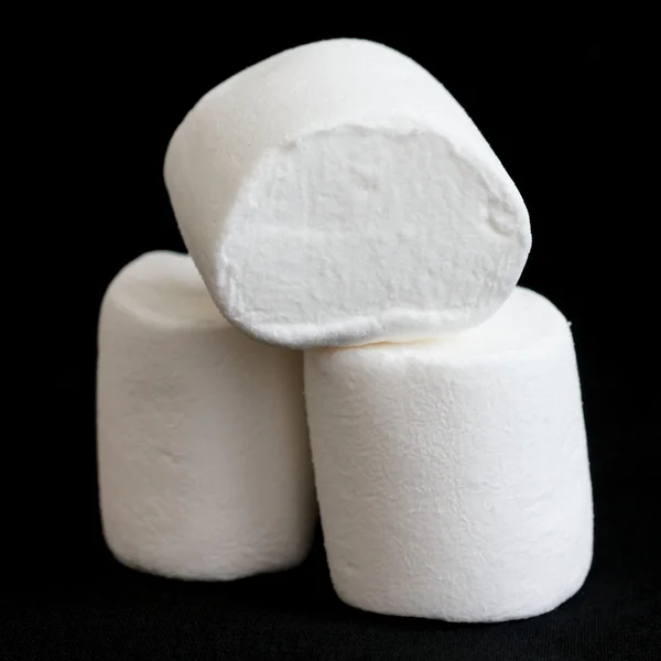 Três marshmallows empilhados e isolados em preto . — Fotografia de Stock