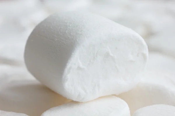 Egyetlen fehér pillecukor más marshmallows ül. elmosódott háttér. — Stock Fotó