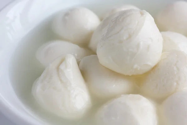 Kleine weiße Mozzarella-Bällchen in einer weißen Schüssel mit Flüssigkeit. — Stockfoto