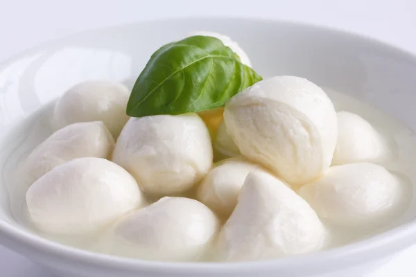 Pequeñas bolas de mozzarella blanca en un plato blanco con líquido . —  Fotos de Stock