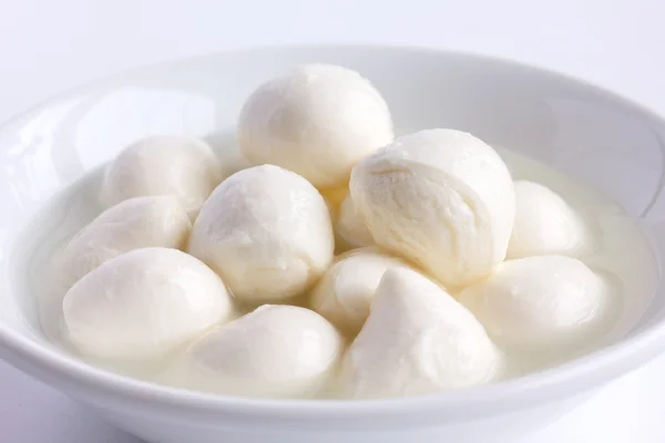 Kleine witte mozzarella ballen in een witte schotel met vloeistof. — Stockfoto