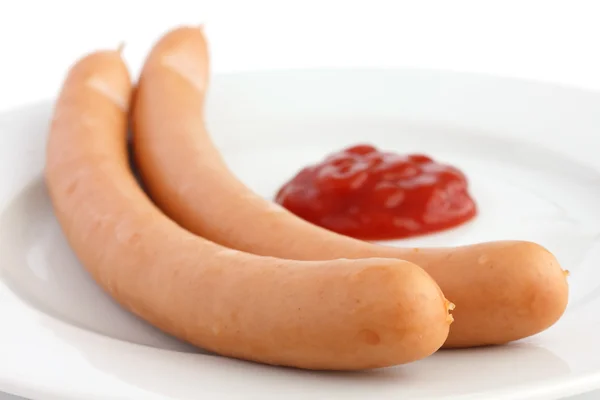 Дві ковбаски на тарілці з кетчупом — стокове фото