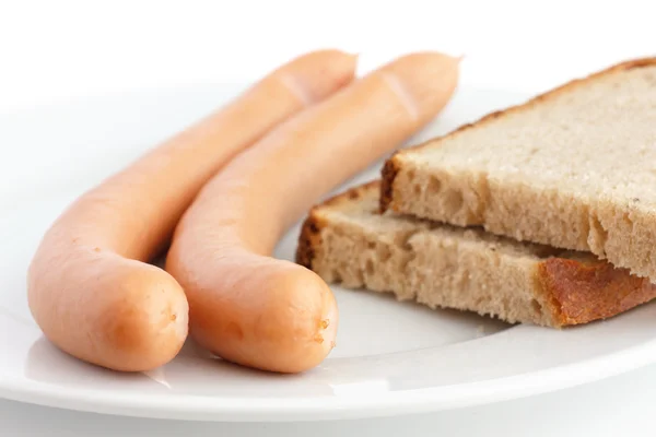 Twee gekookte frankfurter worstjes op een plaat met brood — Stockfoto