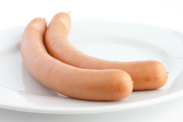 Beyaz arka planlı bir tabakta iki pişmiş frankfurter sosis — Stok fotoğraf