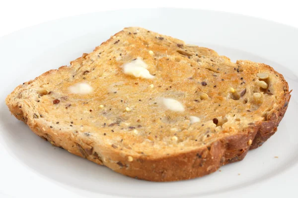Fatia de pão integral de múltiplas sementes torrado e com manteiga — Fotografia de Stock