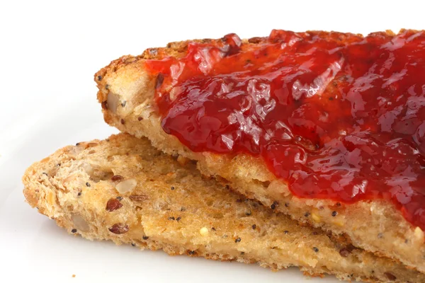 Slice of multi-seed wholegrain bread toasted and buttered with jam — Stock Photo, Image