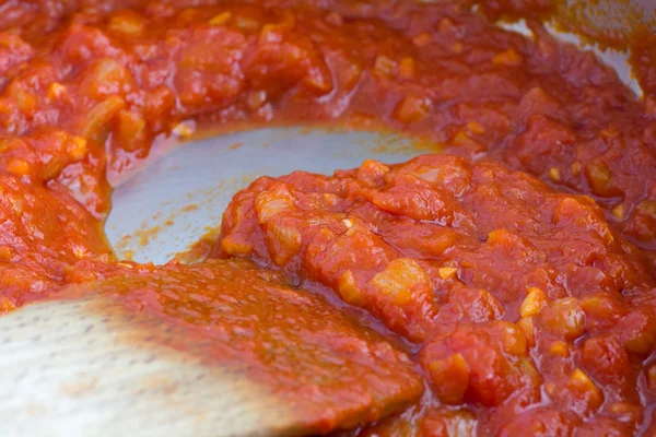 Детали свежеприготовленного томатного соуса в кастрюле с деревянной ложкой . — стоковое фото