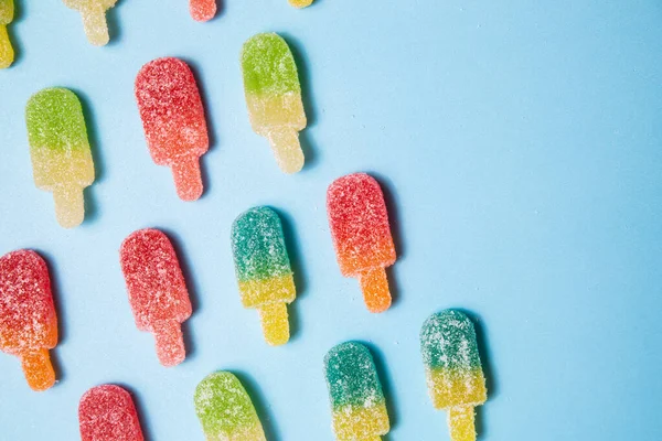 Sugary gummy popsicle candy pattern on blue