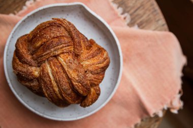 Tarçınlı şekerli çay, fırında pişmiş ekmek, yumuşak pembe bir peçeteye konur.