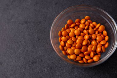 Portakal renkli çikolata kaplı düğmeler koyu bir tabakta serpiştiriliyor - M & M, Smarties, Srinkles