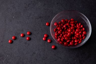 Kırmızı şeker kaplı çikolata düğmesi koyu bir tabakta serpiştiriyor - M & M & M, Smarties, serpiştirmeler