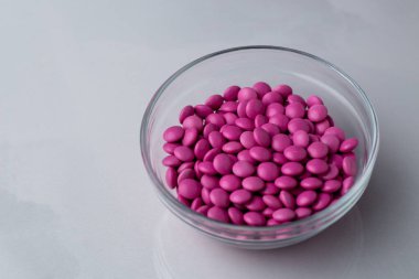Pembe şeker kaplı çikolata düğmeleri parlak mermer bir kaseye serpiştiriliyor - M & M, Smarties, Srinkles