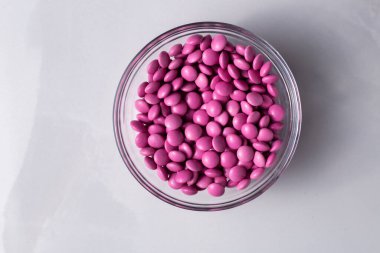 Pembe şeker kaplı çikolata düğmeli mermer bir kaseye serpiştirilmiş M & M & M, Smarties, serpinti