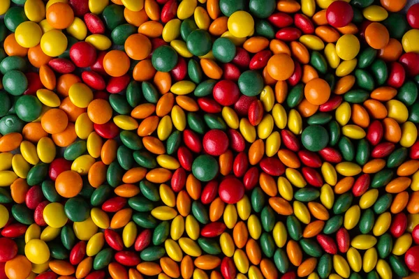 Red, orange, green and yellow candy coated chocolate button sprinkle texture - M&Ms, Smarties, sprinkles