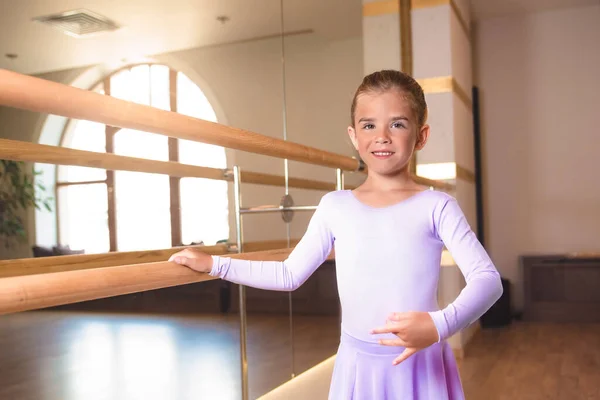 小さな笑顔の女の子がフレームと大きな鏡の近くのバレエ教室でストレッチをしています — ストック写真
