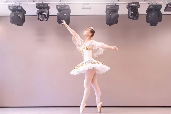 若いクラシックバレエダンサーでスタジオはティプトに立っています 若い美しい優雅なCucasian Balelina練習バレエの位置でTutuスカートの白い白鳥 — ストック写真