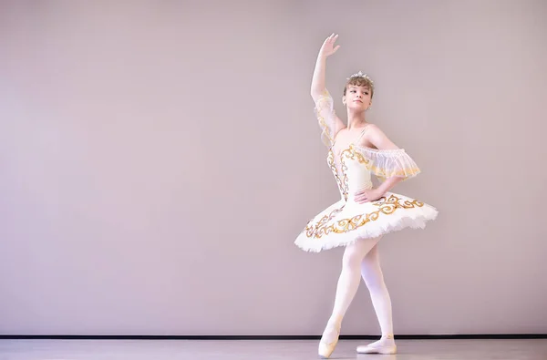 若いクラシックバレエダンサーでスタジオはティプトに立っています 若い美しい優雅なCucasian Balelina練習バレエの位置でTutuスカートの白い白鳥 — ストック写真