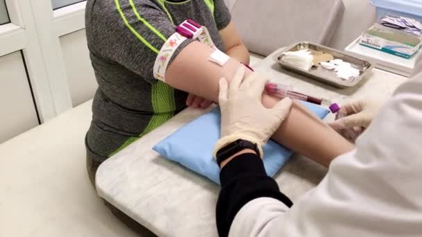 Enfermeira tira sangue de uma veia de uma mulher em uma camiseta preta. — Vídeo de Stock