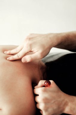 Bir erkek masör spa tedavisini özel bir masaj silindiriyle gerçekleştirir. Kanepeye yüzüstü uzanmış genç bir kadın için..