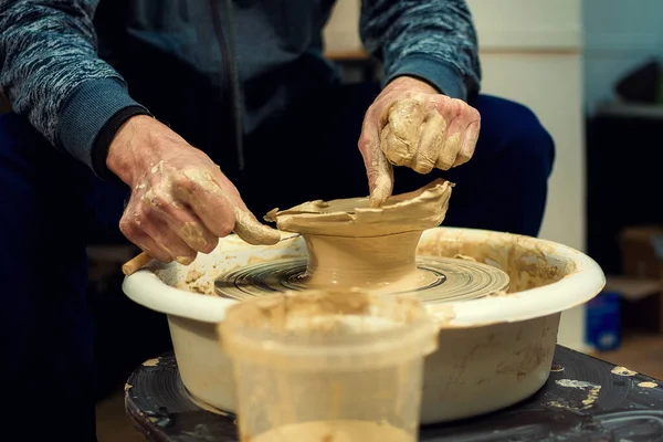 Les mains des potiers hommes se forment par un pot d'argile sur une roue de potiers. Le potier travaille dans un atelier. — Photo